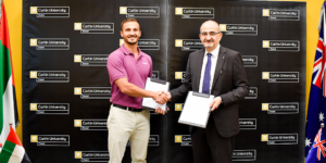 Representatives from Curtin University Dubai and Odoo smiling and holding the signed Memorandum of Understanding (MoU) document during the official partnership ceremony.
